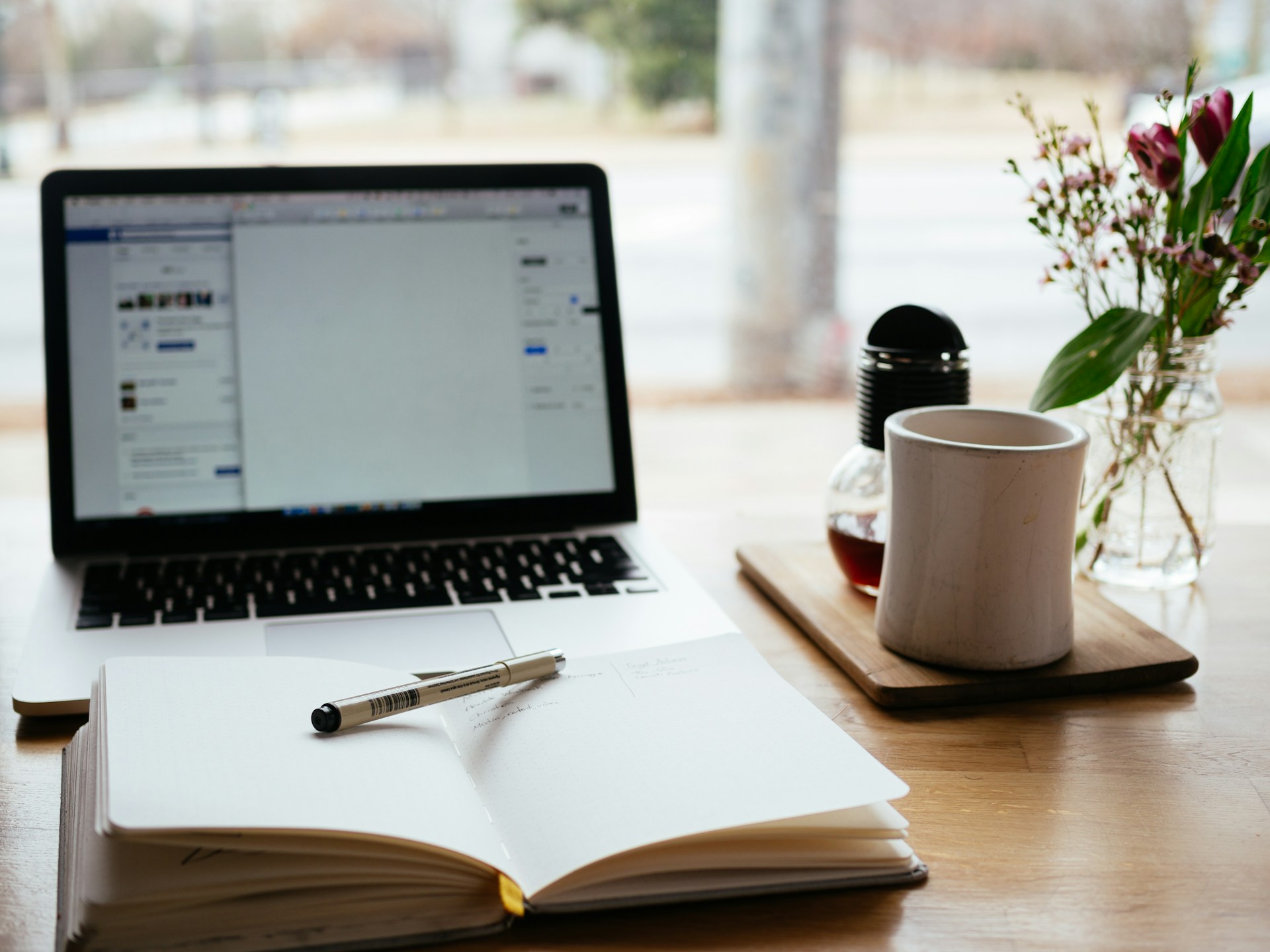Heller Arbeitsplatz mit Laptop und Notizbuch – Symbolbild für die Verwaltung